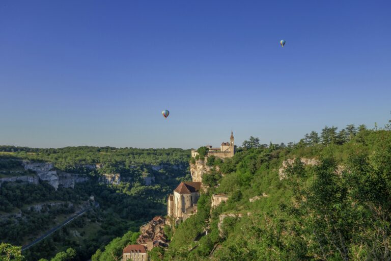 two hot air balloons flying over a cliff